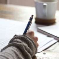 A hand holding a pen writing on paper